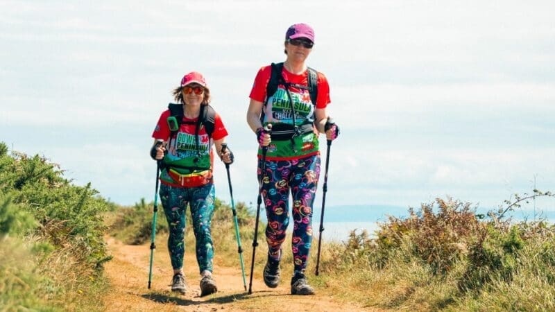 two women hiking on a path near a coastline