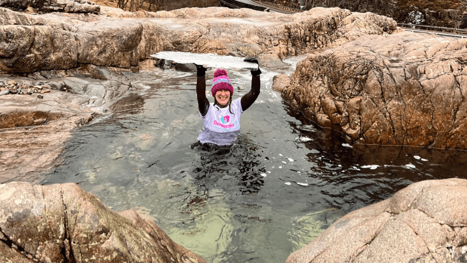 Lady in cold water with a Dementia UK top holding ice above her head