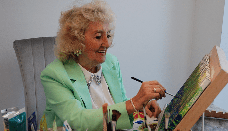 Sylvia paints on a canvas
