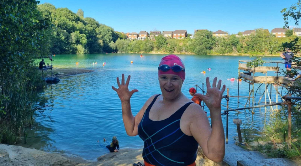 Lady in swimming costume sitting on the side of a lake