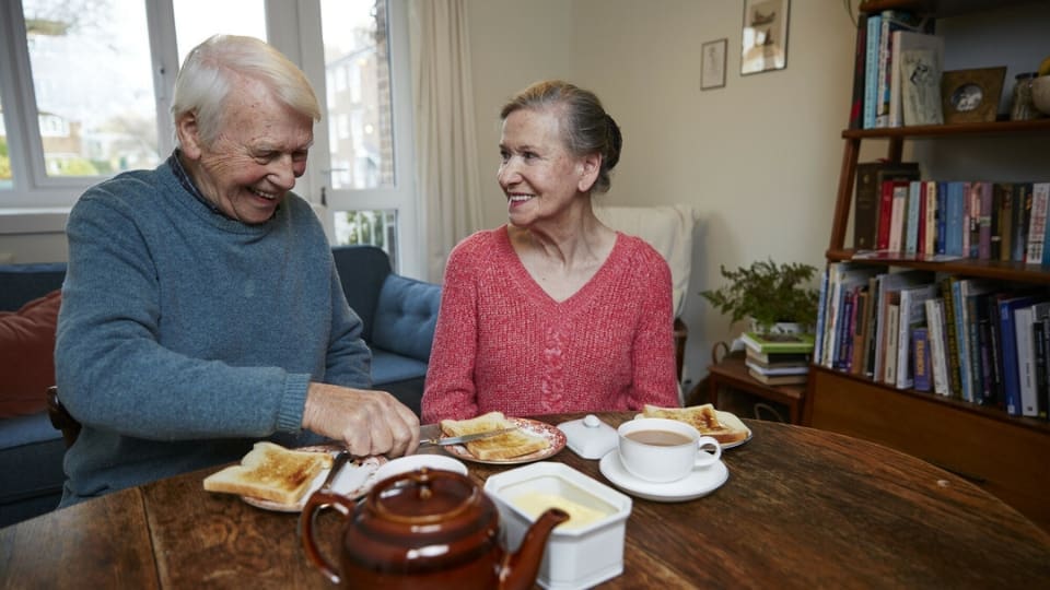 A carer makes a meal of tea and toast in the morning at home.