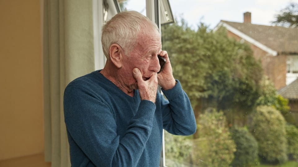 Older man on telephone looking out the window