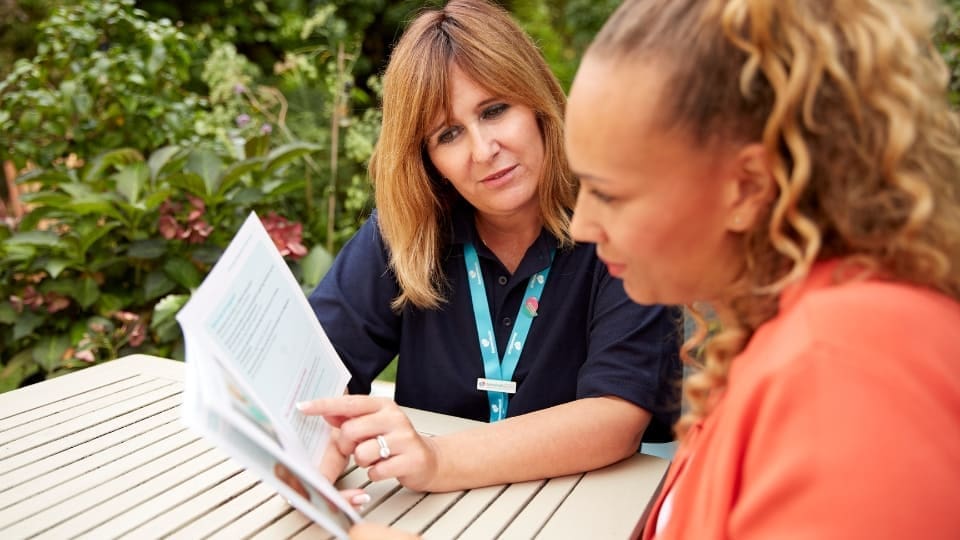 Admiral Nurse shows woman a support leaflet